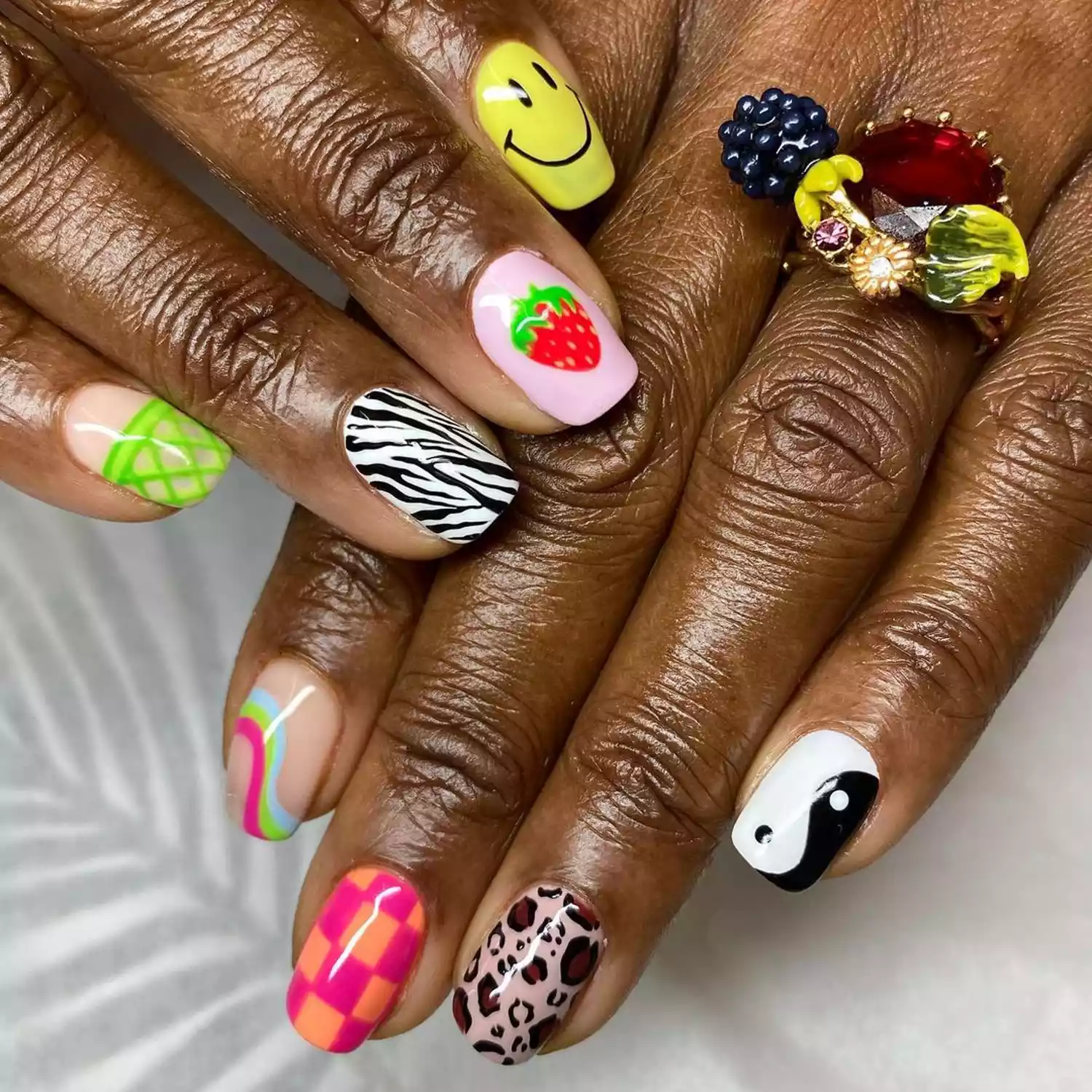 Mismatched manicure with smiley faces, zebra print, strawberry and swirl designs