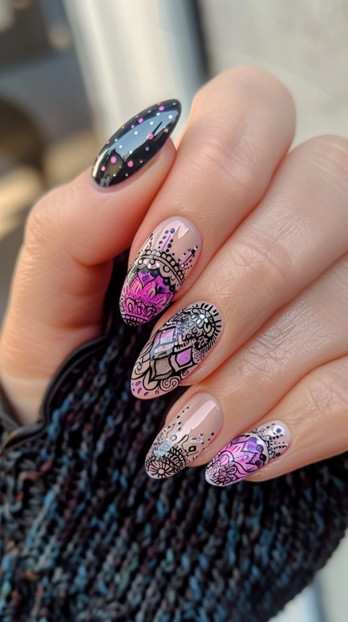 This nail design features a striking combination of a black base with vibrant pink mandala patterns, contrasted with nude nails detailed with black geometric designs and dots, creating a bold bohemian look.