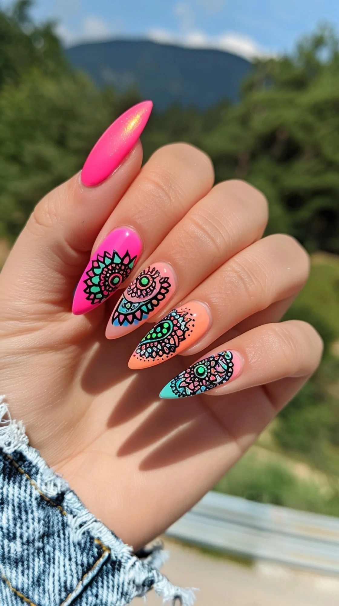 Vivid gradient nails transitioning from hot pink to turquoise, each adorned with intricate black mandala patterns centered around a lime green dot, exuding a vibrant and energetic bohemian spirit.