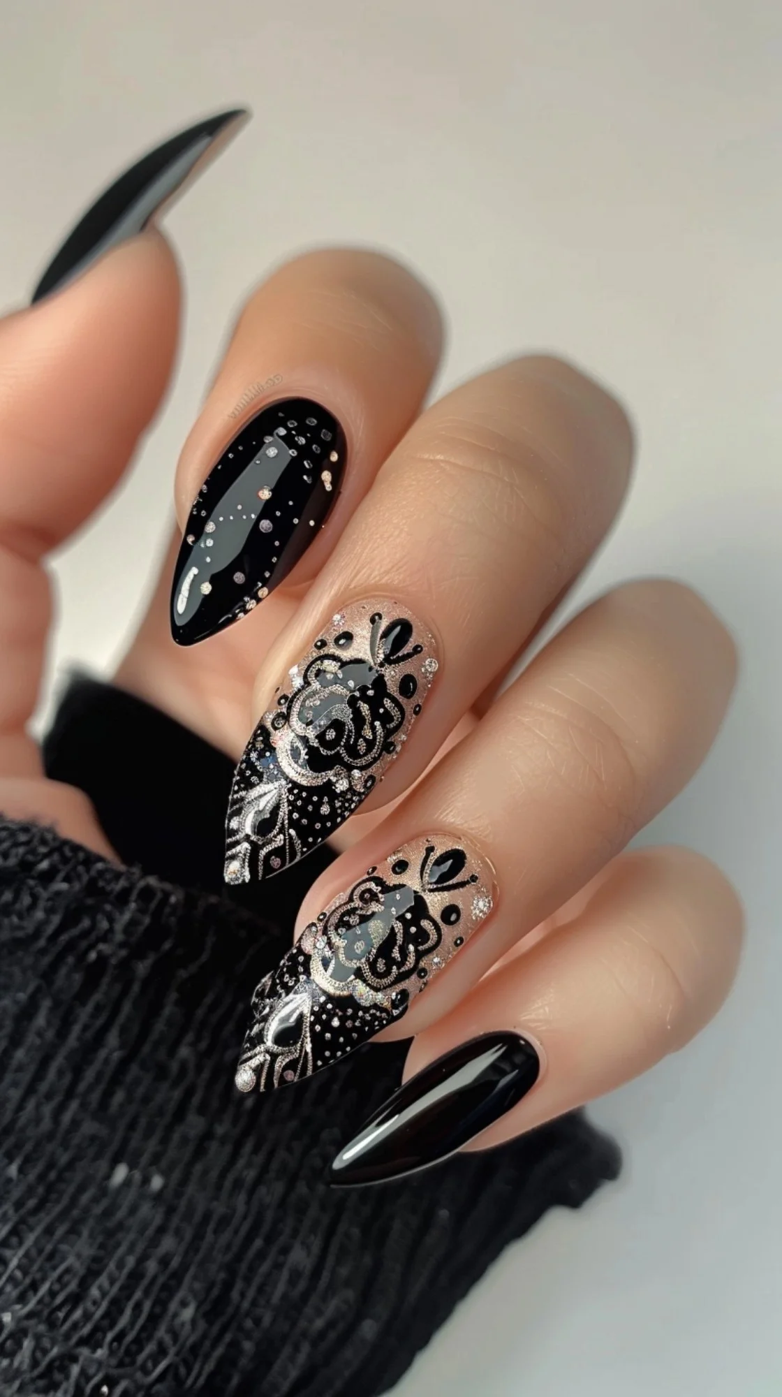 Chic boho nail art with alternating black and glittery silver bases, detailed with white paisley and mandala designs, enhanced by precise dotwork that creates a stunning contrast and a touch of elegance.