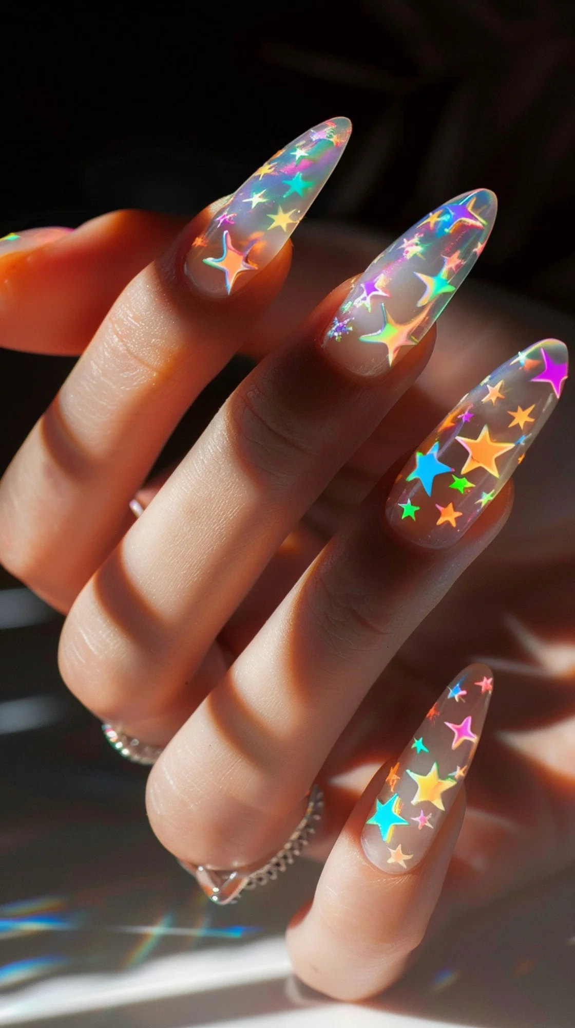 This lively nail art features a holographic base that catches light and colors brilliantly. Multi-colored star stickers of various sizes are scattered playfully across the nails, creating a dynamic, kaleidoscopic effect that is both bold and festive, reminiscent of a vibrant, star-studded party.