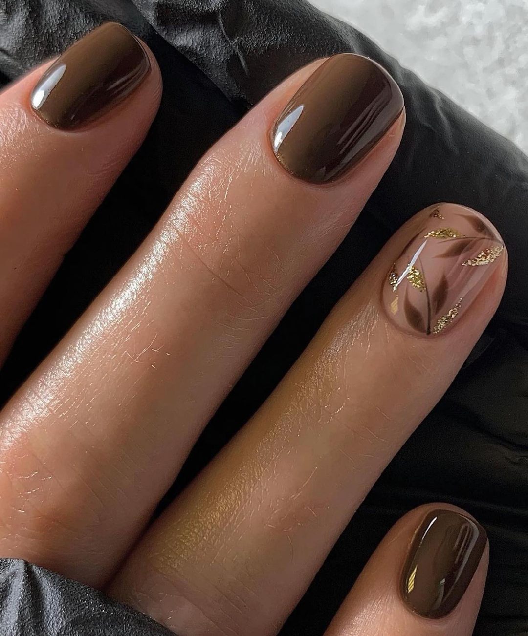 Short brown nails with leaf nail art.