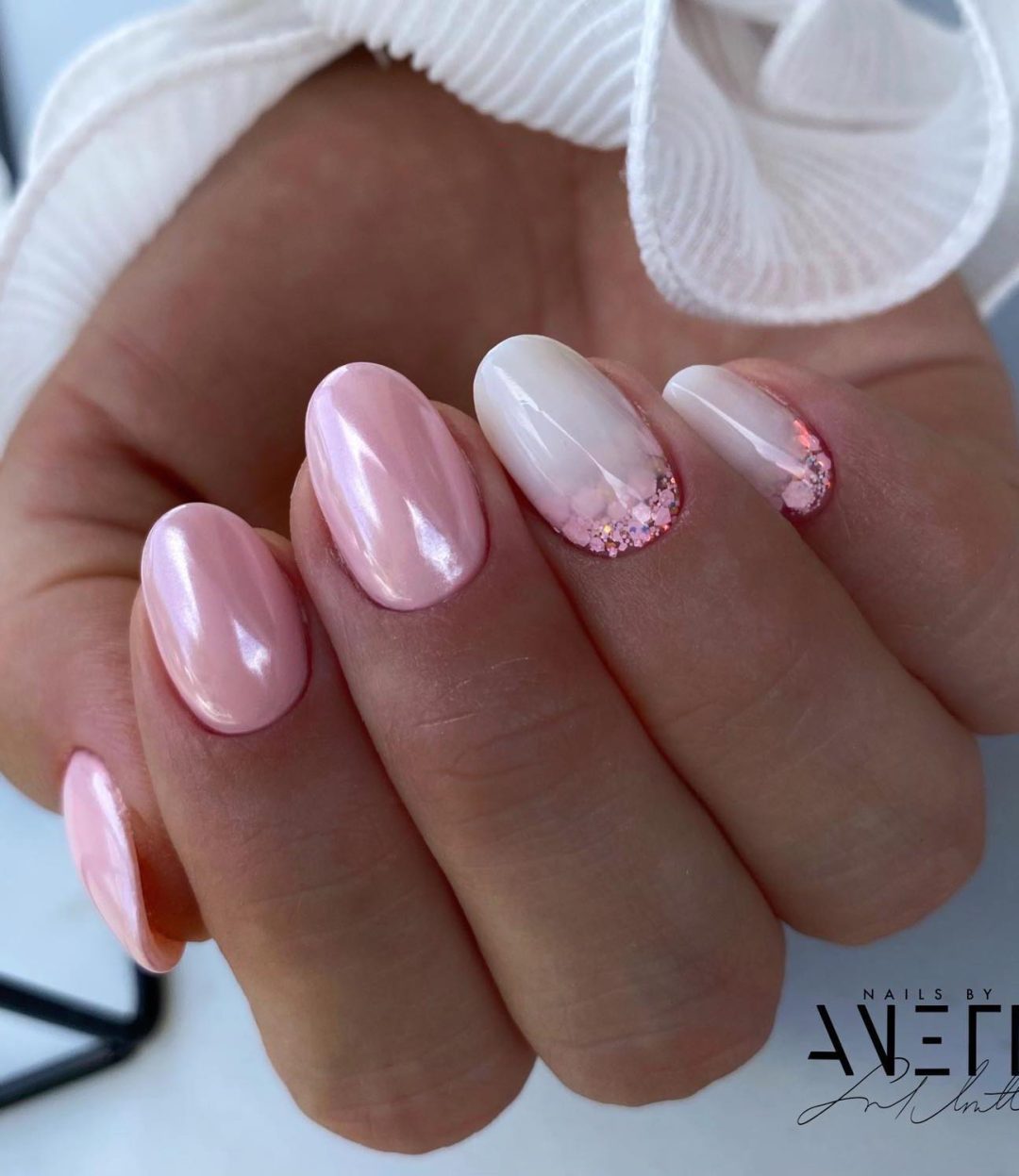 Short white and light pink ombre nails with glitter.