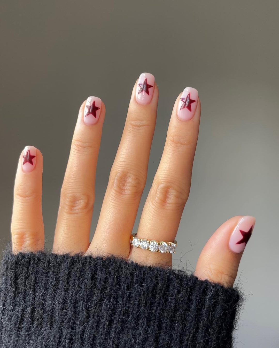 Burgundy star nail art on short nails.