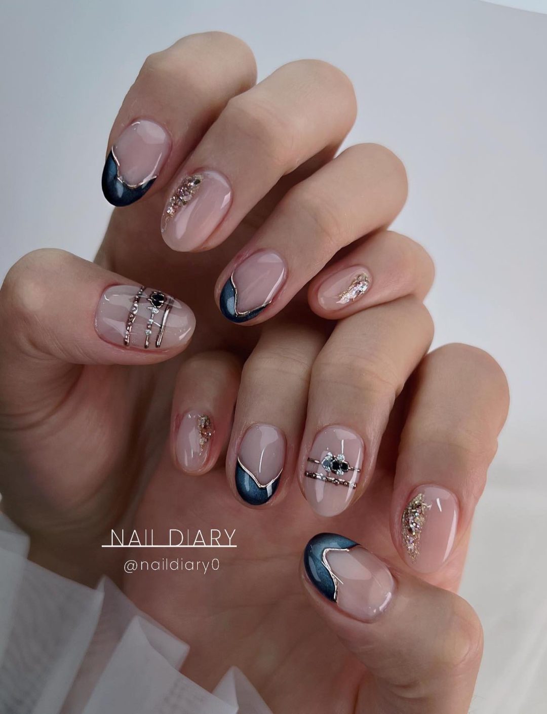 Short neutral nails with navy blue and silver details.