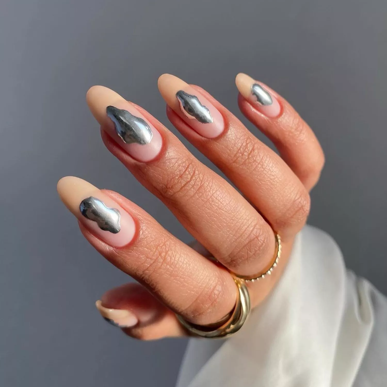 Hand with silver chrome blobs in the center of the nail.