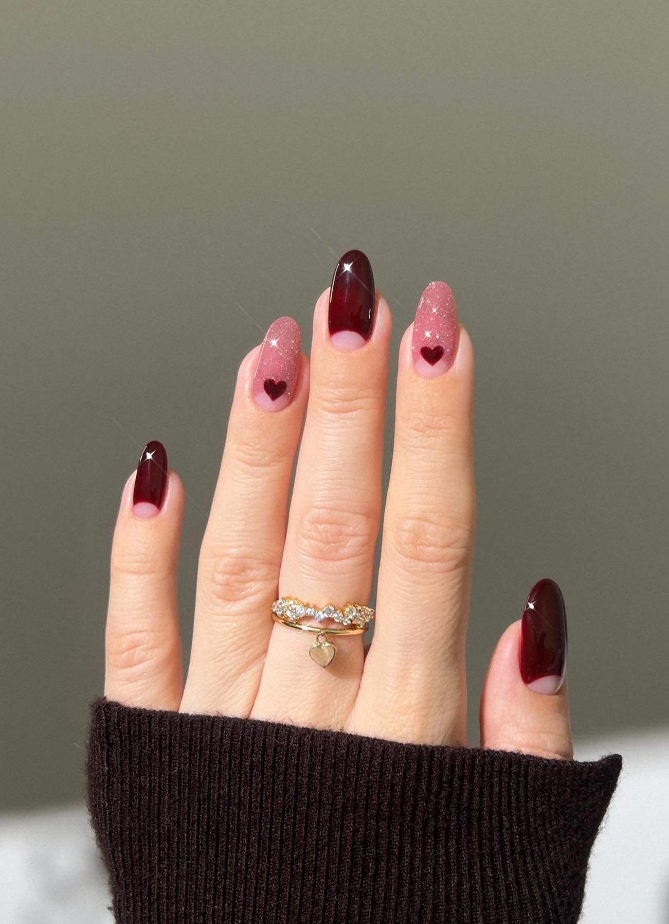 Pink and burgundy nails with hearts and glitter.