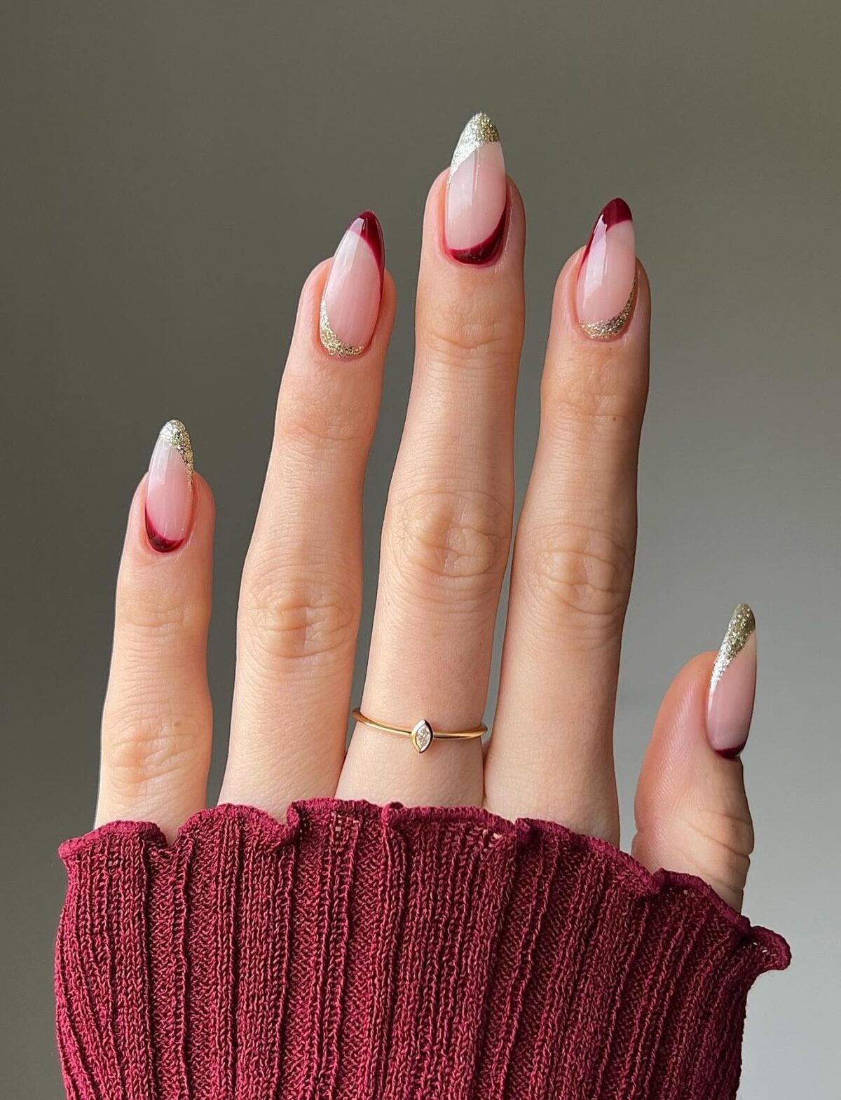 Minimalist burgundy and gold nails on a clear base.