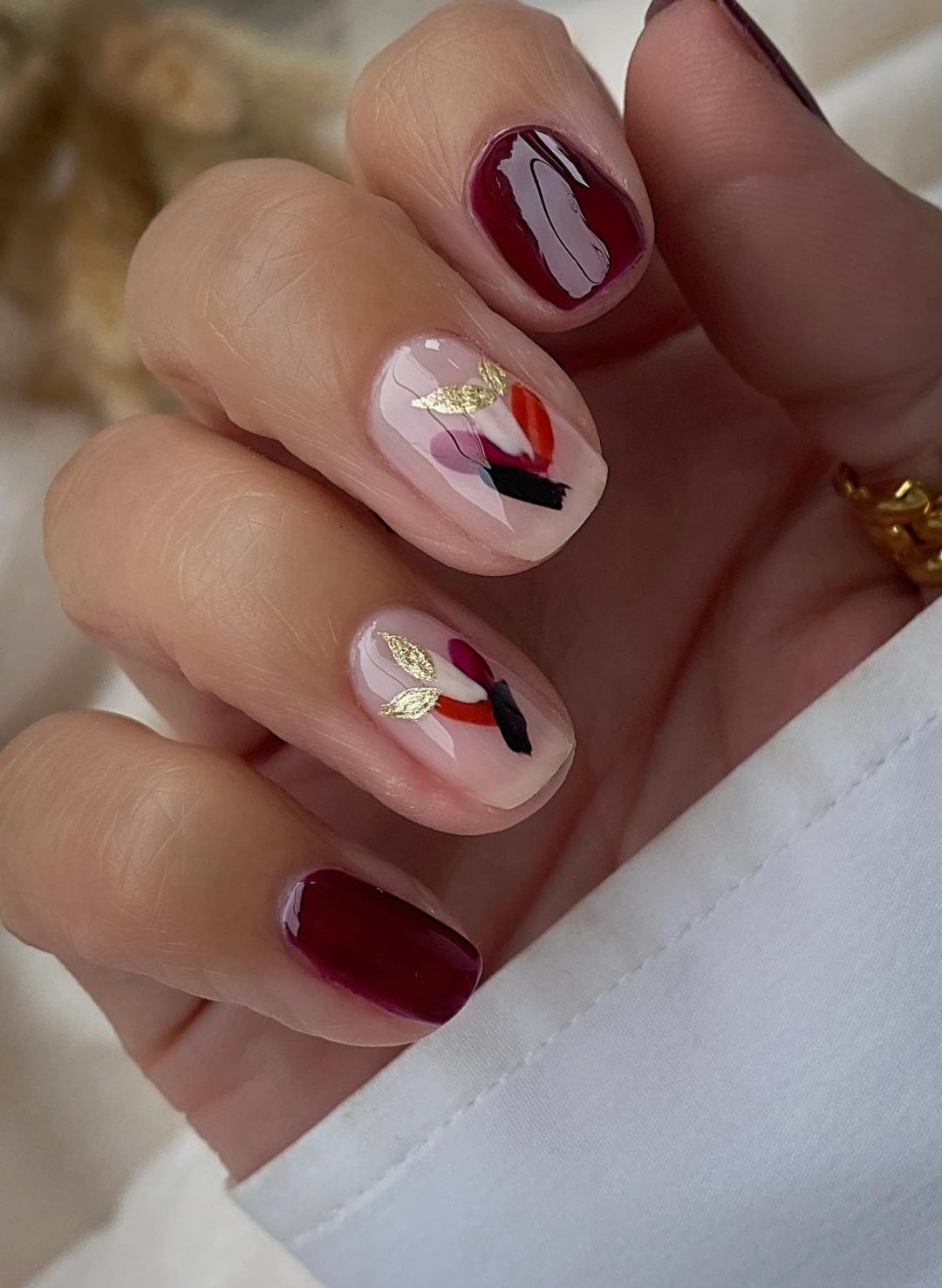 Short burgundy nails with abstract nail art.