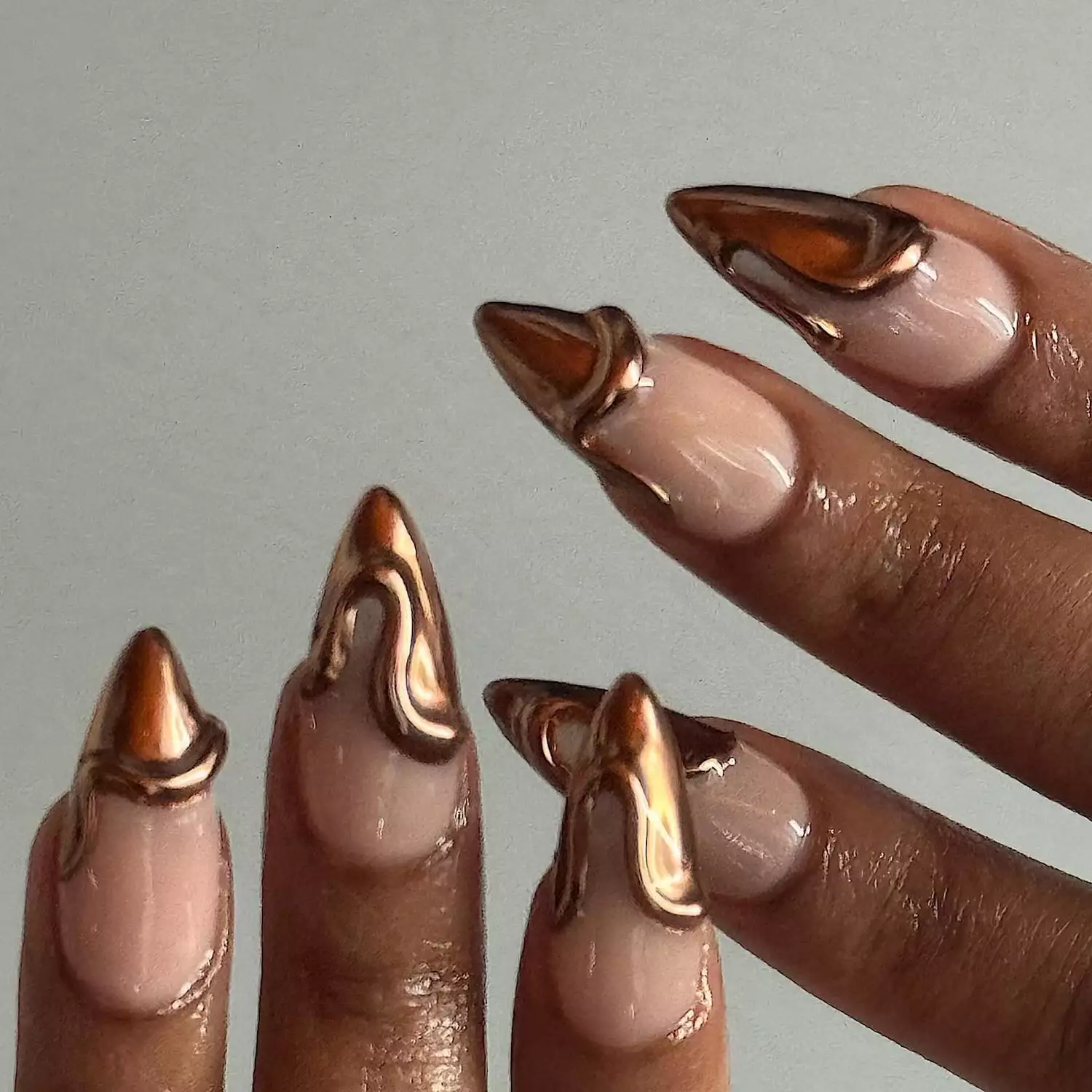 Hand with stiletto shaped nails with copper chrome French tips