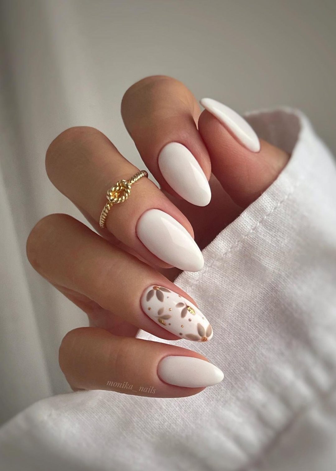 White almond shaped nails with beige flower art.