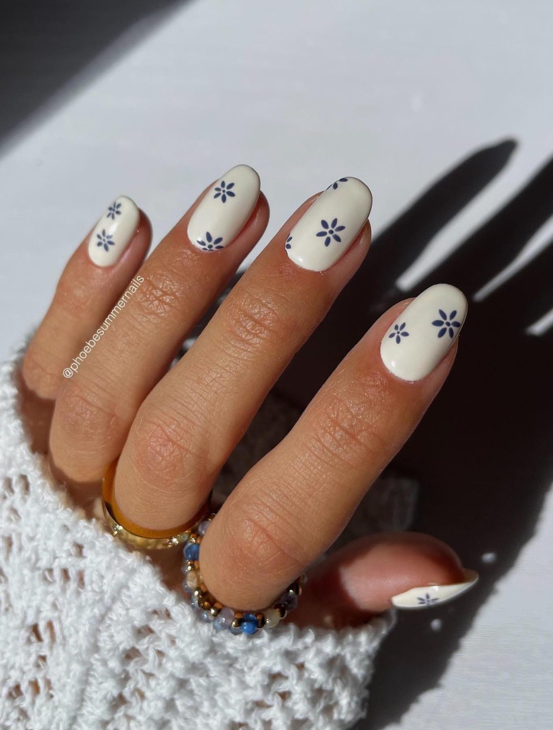 Short white nails with blue daisies.